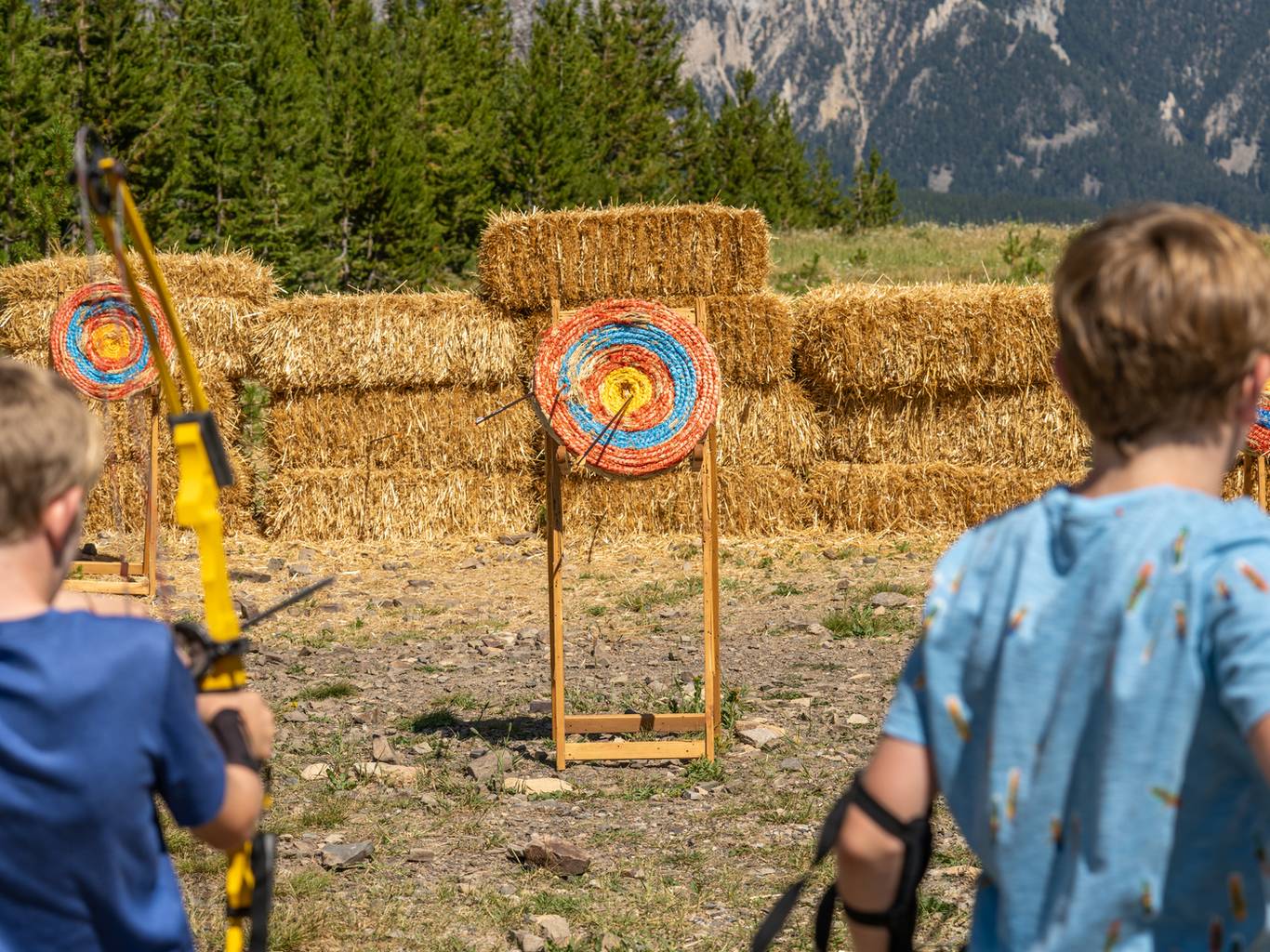 Two kids shooting arrows at an archery range