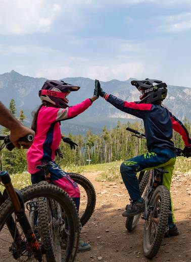 Two girls on their mountain bikes high-fiving