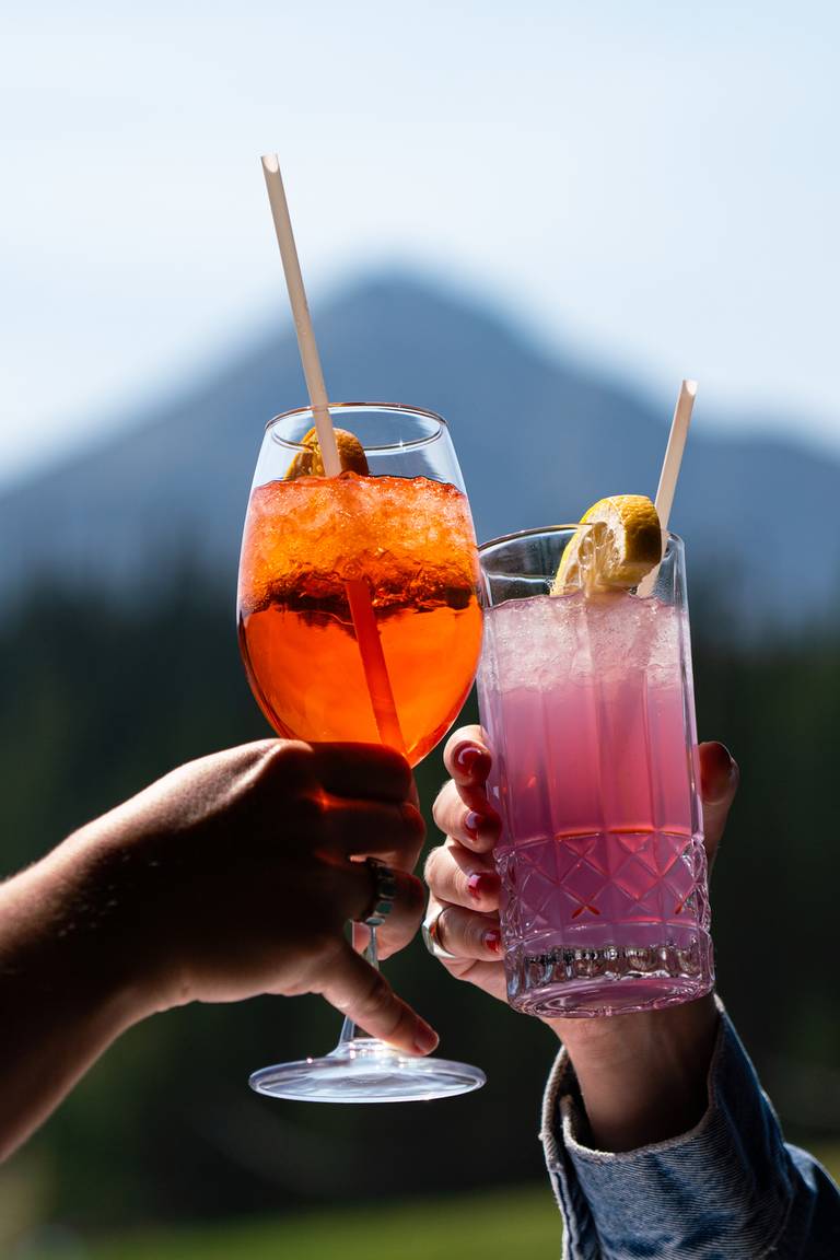 People cheersing cocktails in front of Lone Peak in sumer