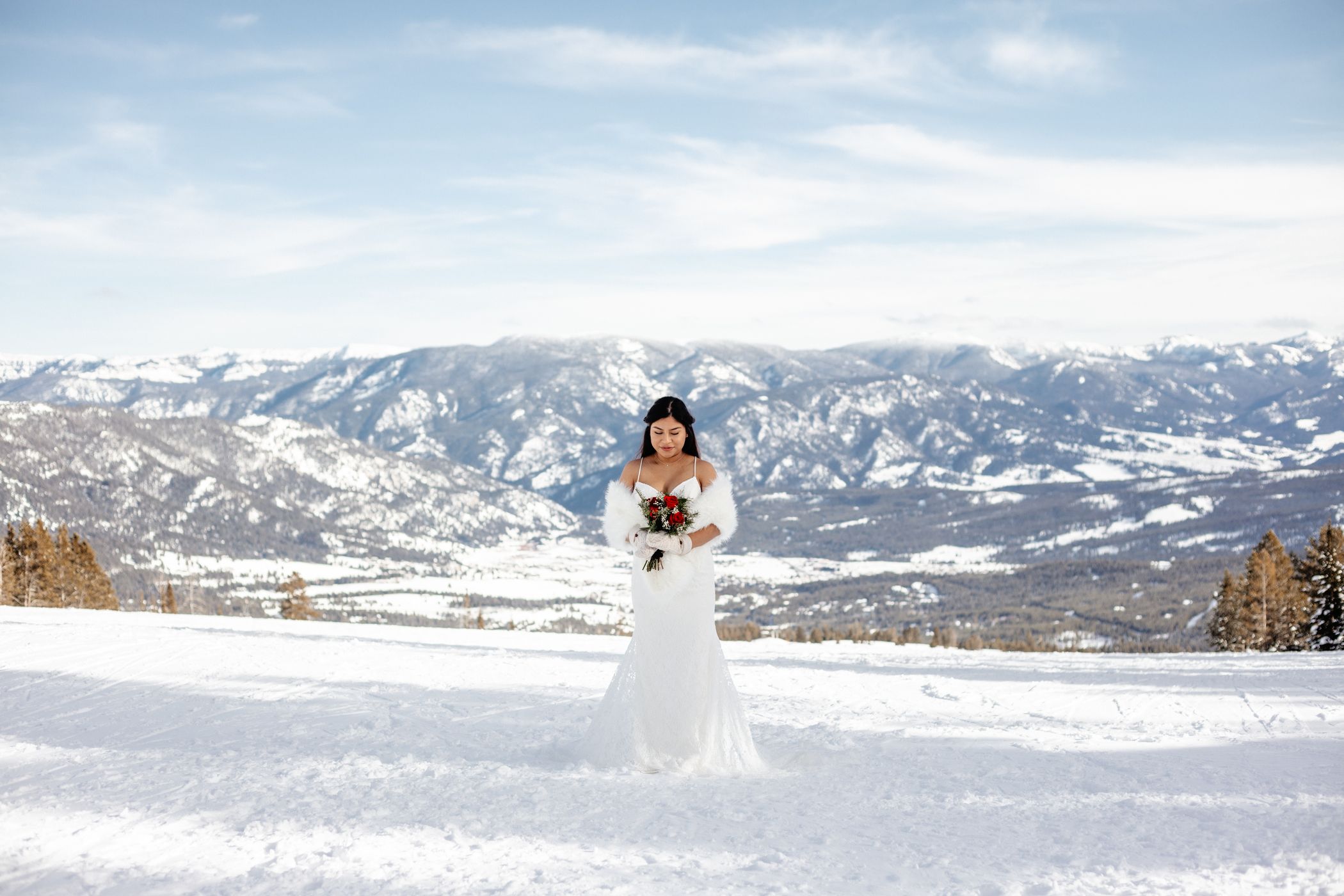 Woman in a wedding dress surrounded by snow and mountains