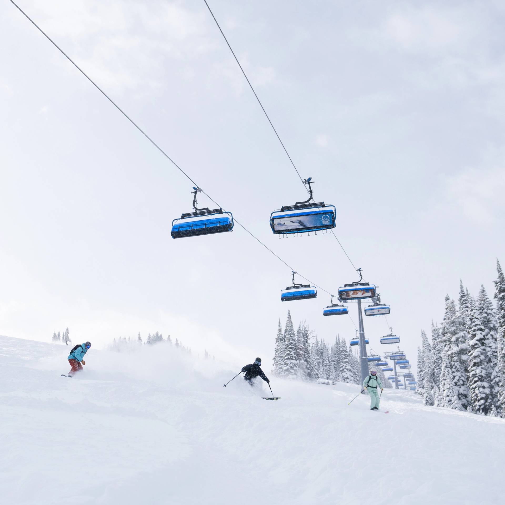 Skiers and snowboarders in powder underneath Ramcharger 8