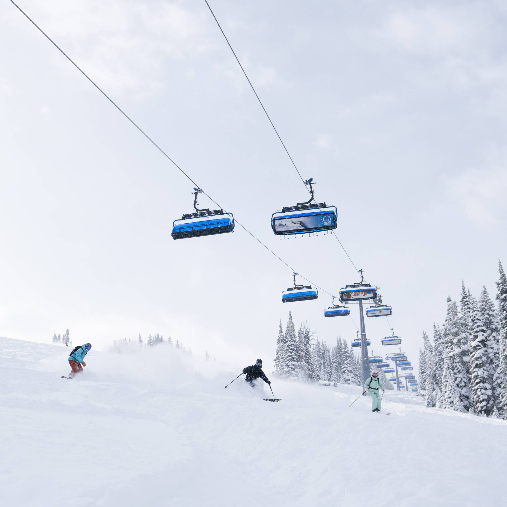 Skiers and snowboarders in powder underneath Ramcharger 8