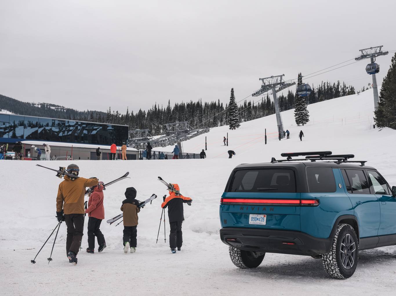 Family with ski gear next to a Rivian SUV at Big Sky Resort