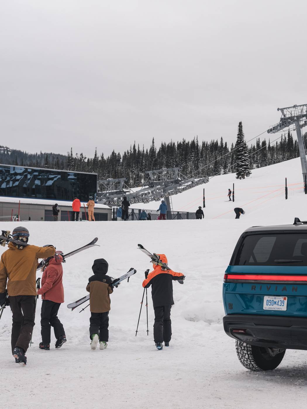 Family with ski gear next to a Rivian SUV at Big Sky Resort