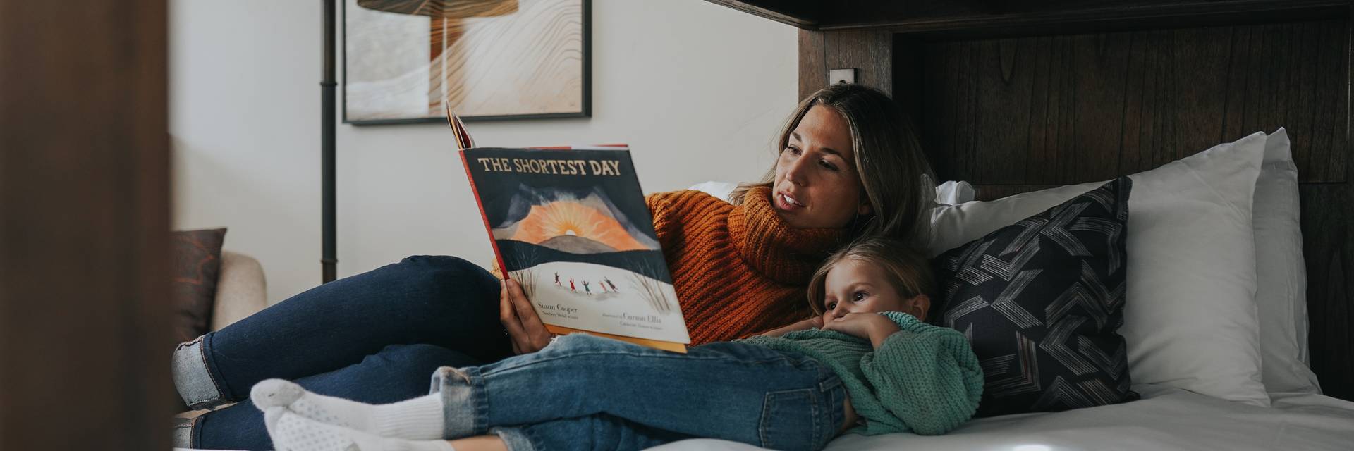 Mother and daughter reading in a hotel bed