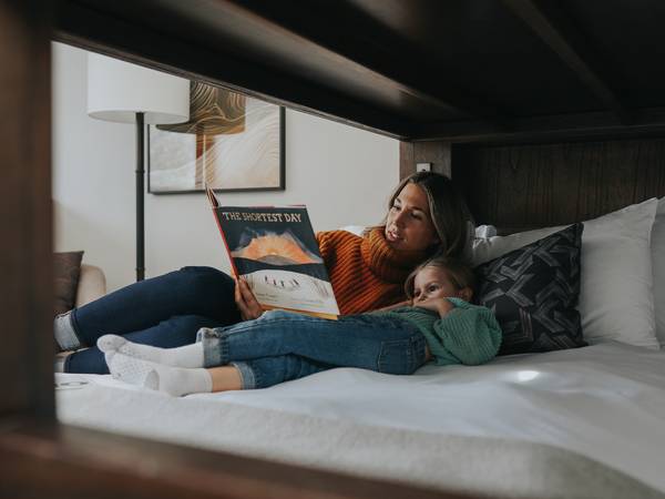 Mother and daughter reading in a hotel bed
