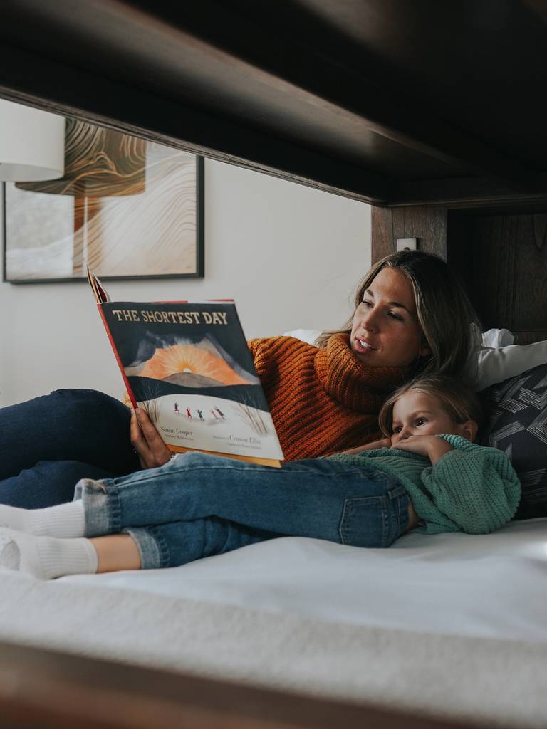 Woman and her daughter reading a book in bed