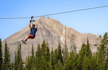 Man on a zipline in front of Lone Peak