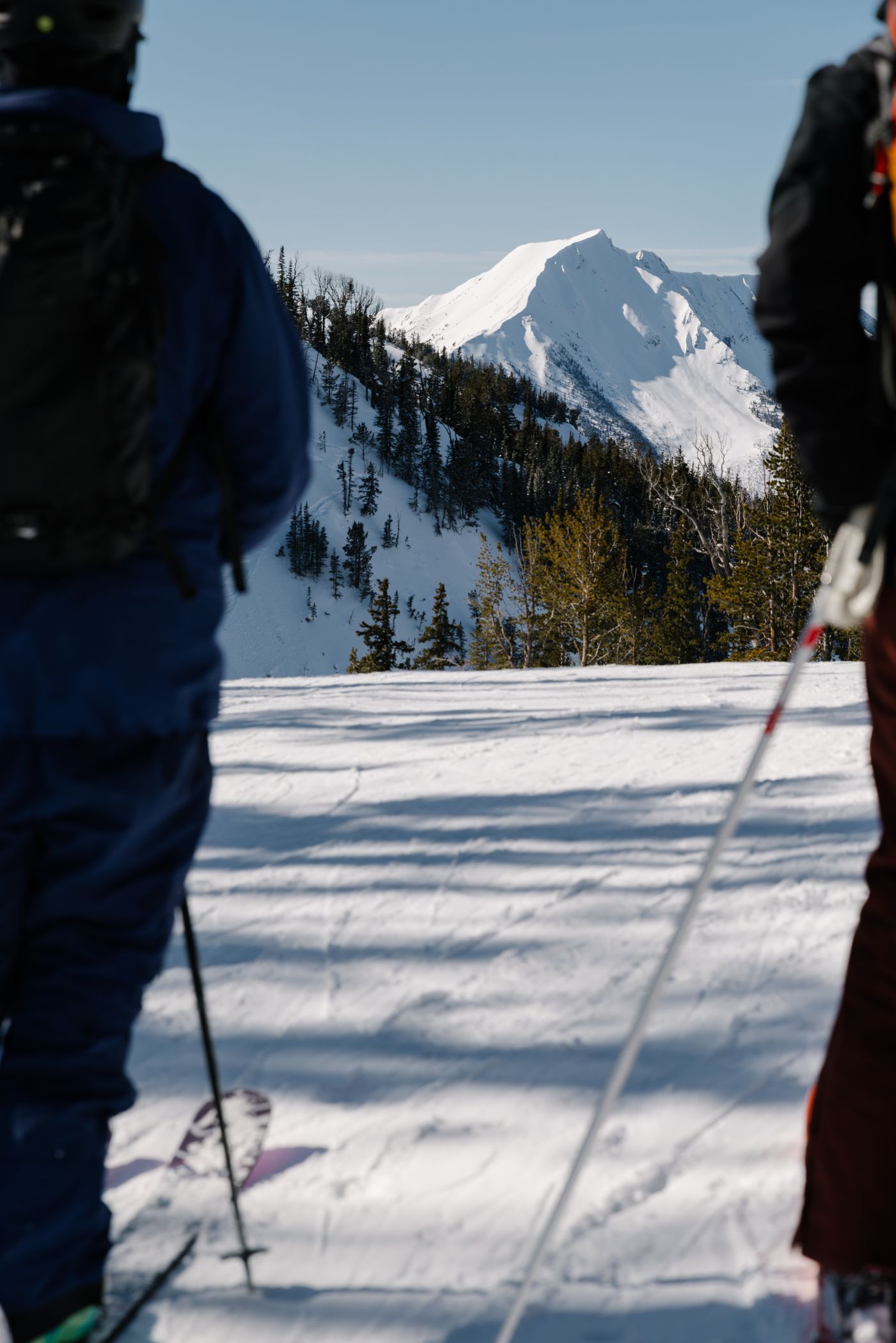 View of a mountain between the silhouettes of two skiers