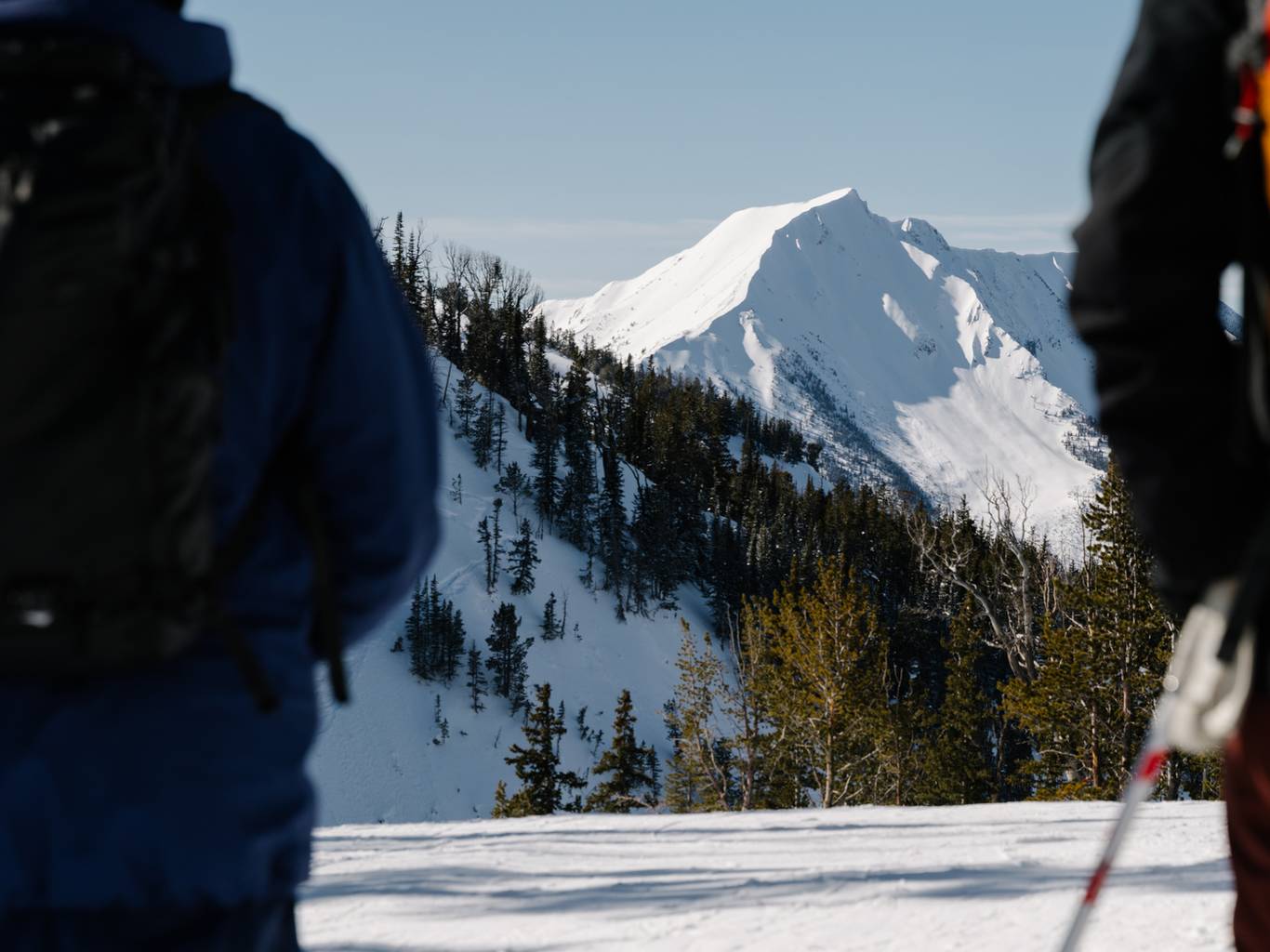 View of a mountain between the silhouettes of two skiers