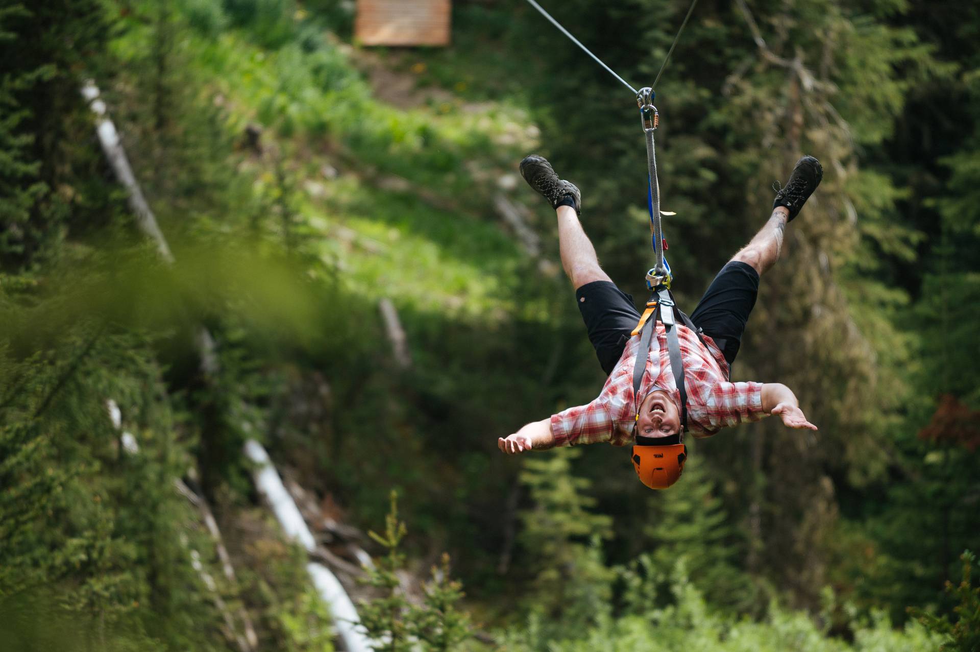 Man hanging upside-down on a zipline