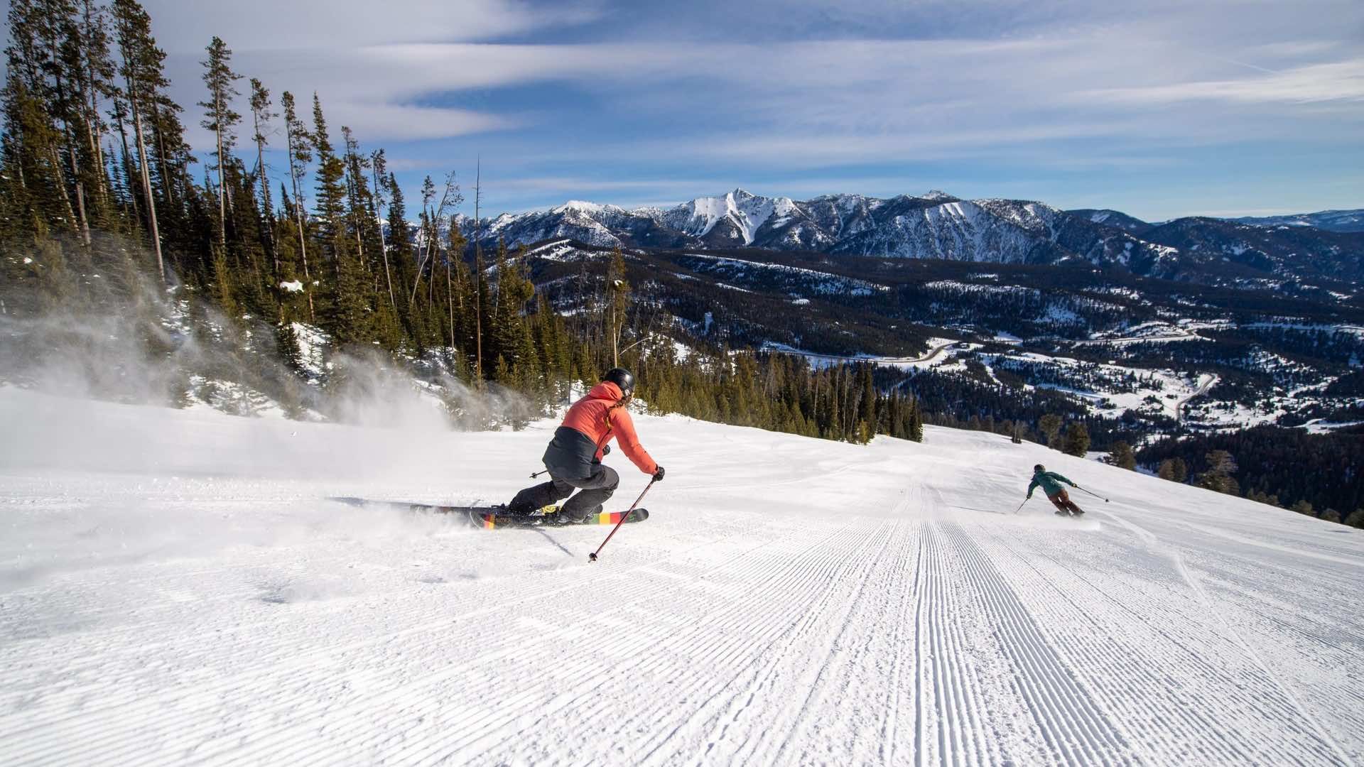 Two skiers carve down a groomer in Big Sky