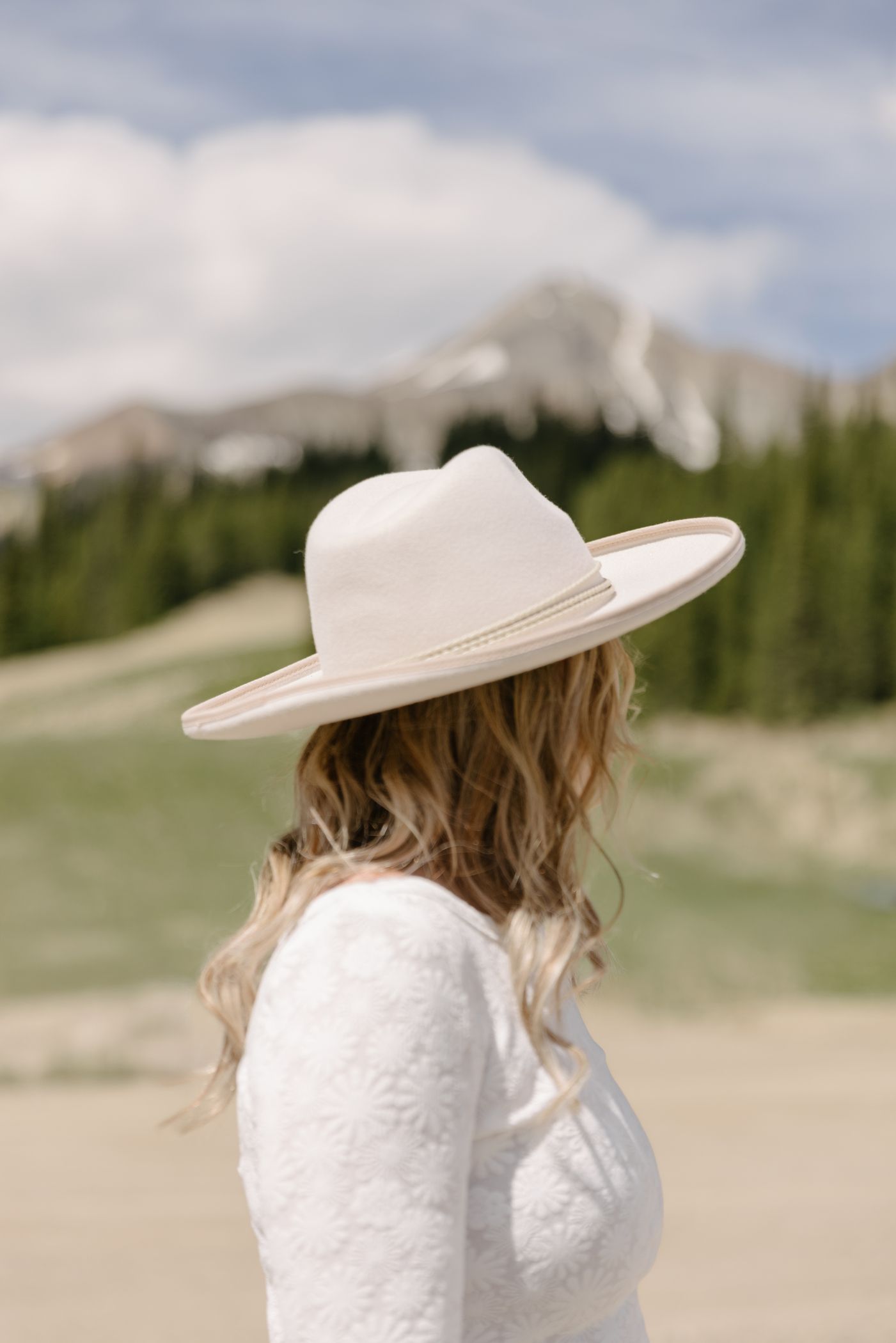 Woman in a felt hat looking out at the mountains