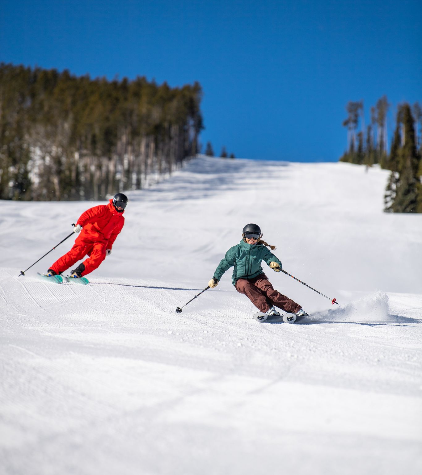 Two skiers on a groomed run