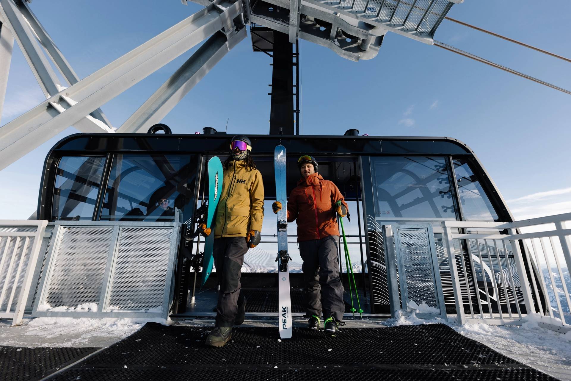 Skier and snowboarder stepping off of the Lone Peak Tram