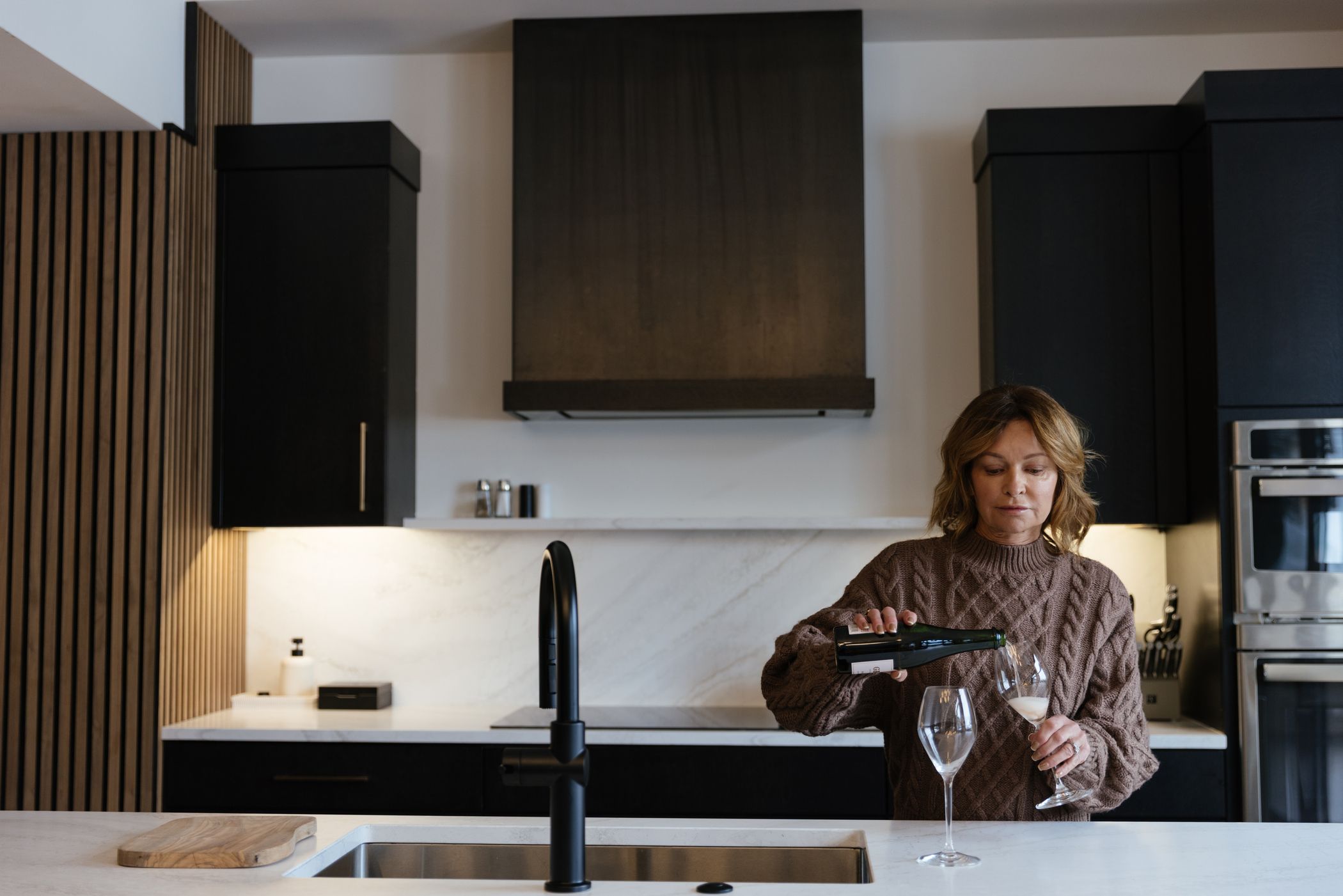 Woman pouring wine glasses in a kitchen