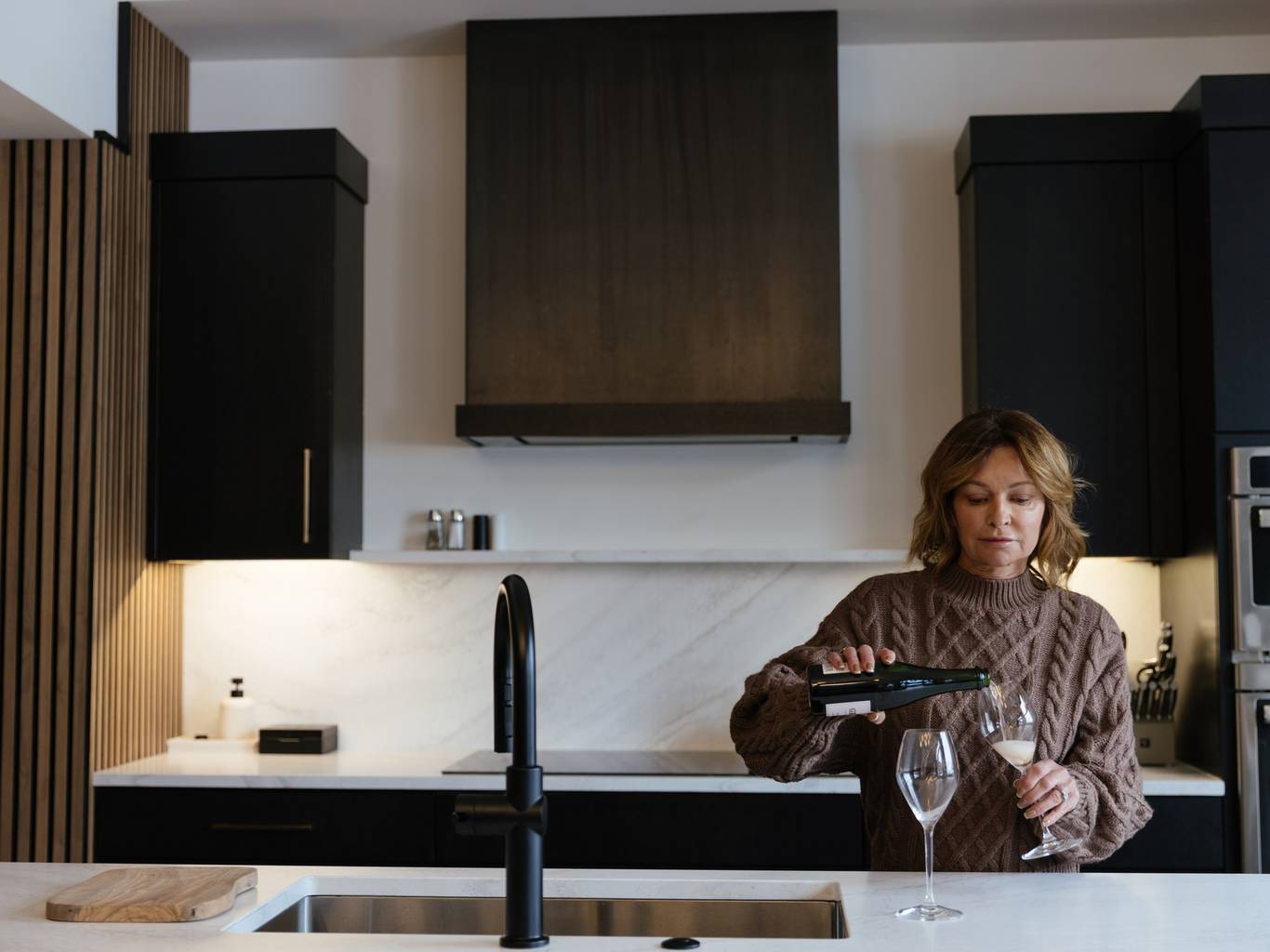 Woman pouring wine glasses in a kitchen