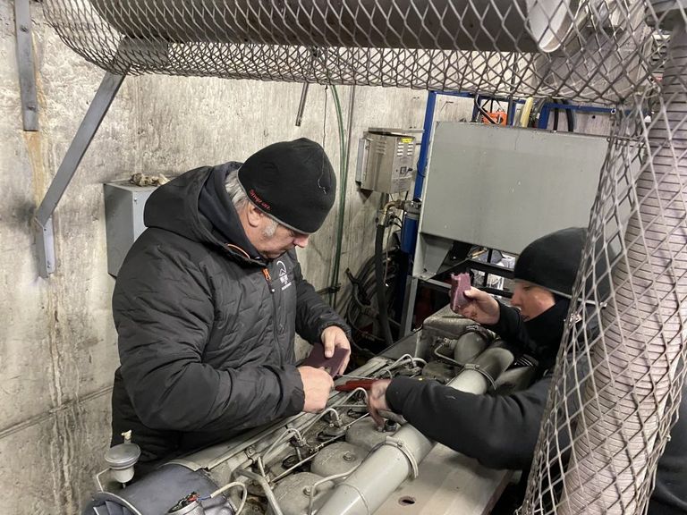 Two lift maintenance members clean the tram engine