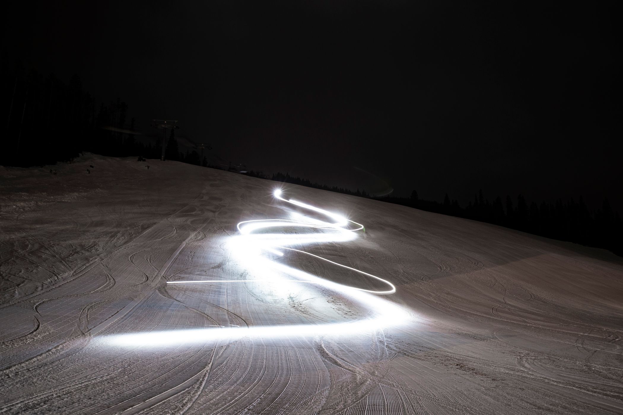 A long exposure photo of lights in the pattern of ski turns