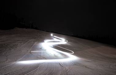 A long exposure photo of lights in the pattern of ski turns
