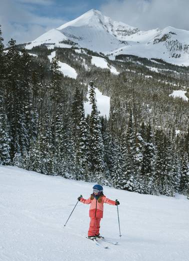 Girl in ski gear with Lone Peak in the background