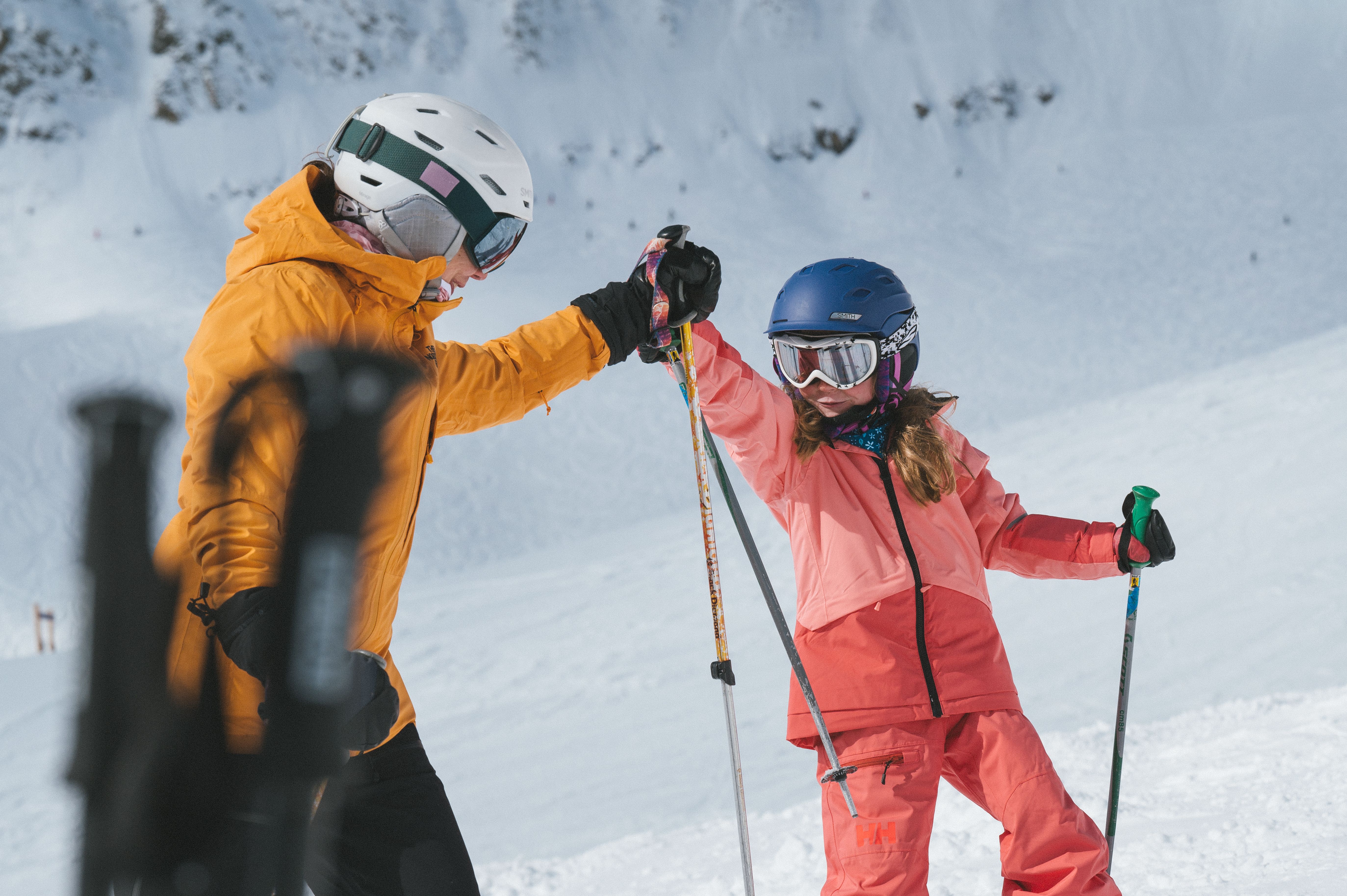 Girl and her parent in ski gear high-fiving