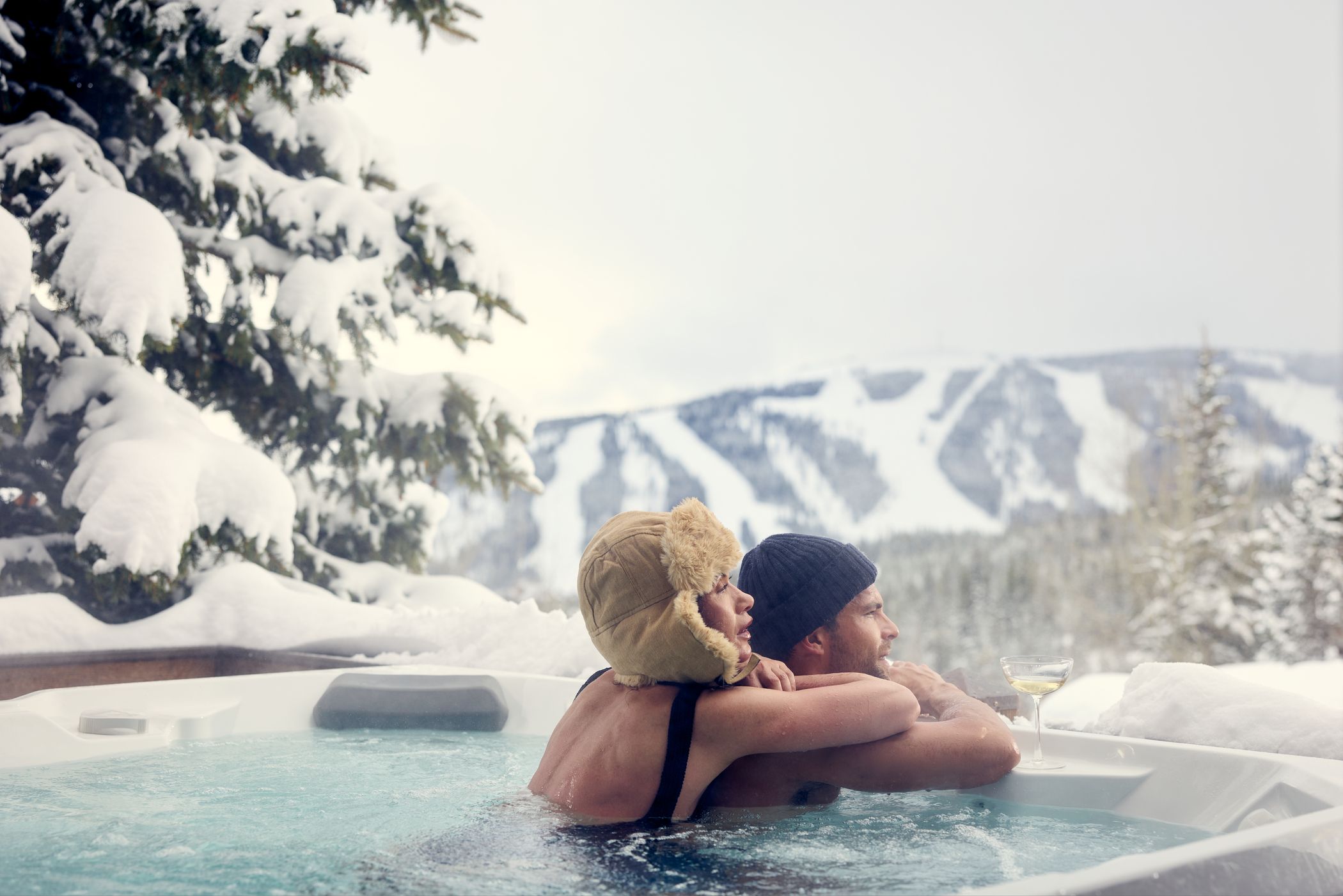 Couple in a hot tub with ski runs in the background