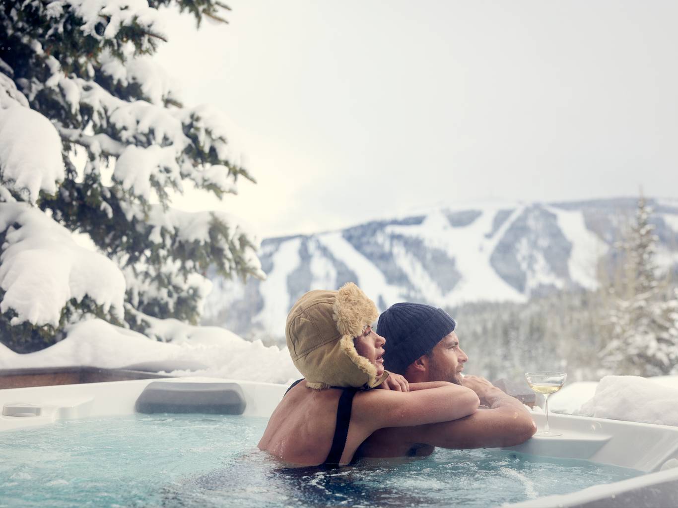 Couple in a hot tub with ski runs in the background