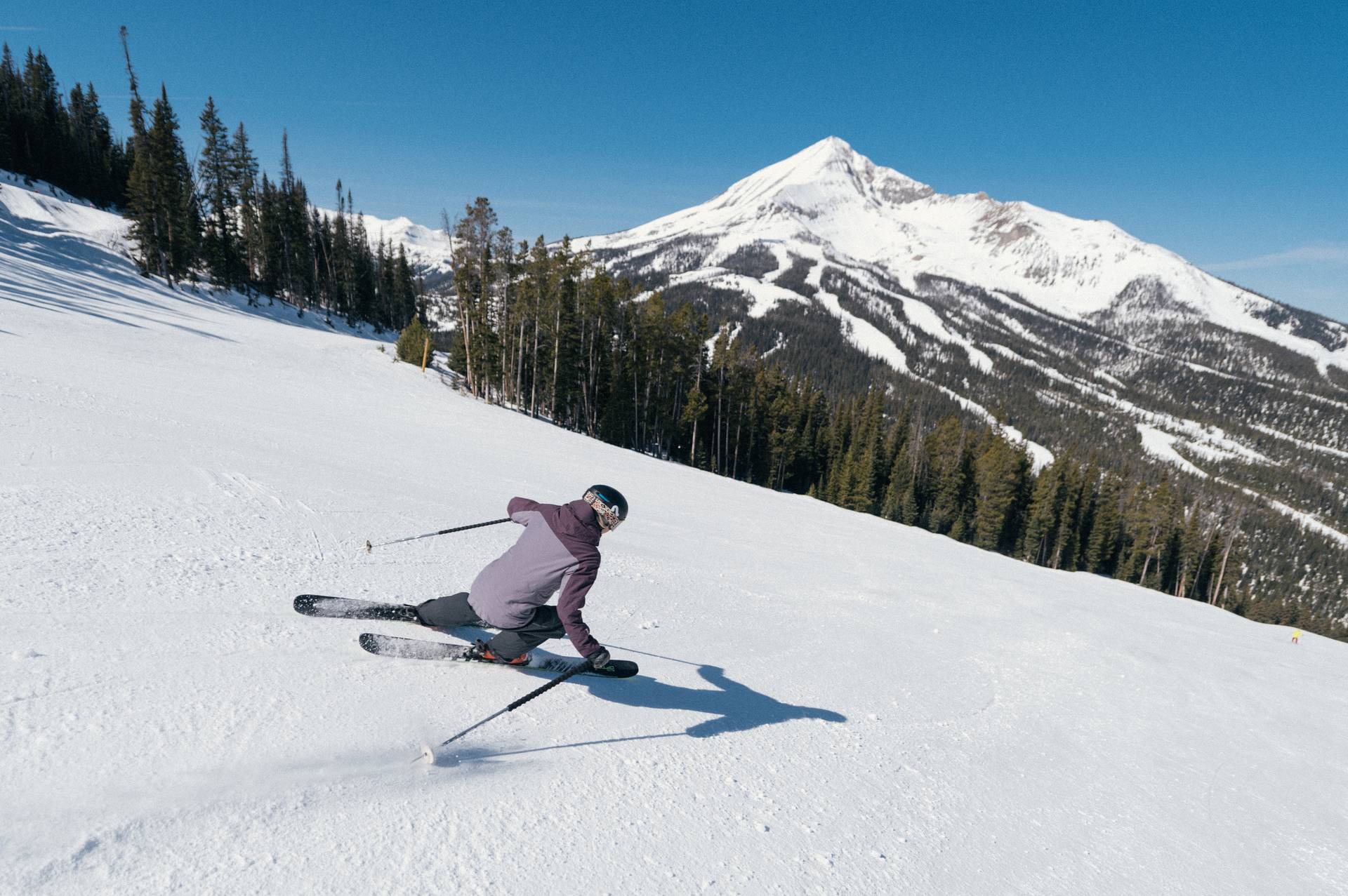 Skier on a groomed run with Lone Mountain in the background