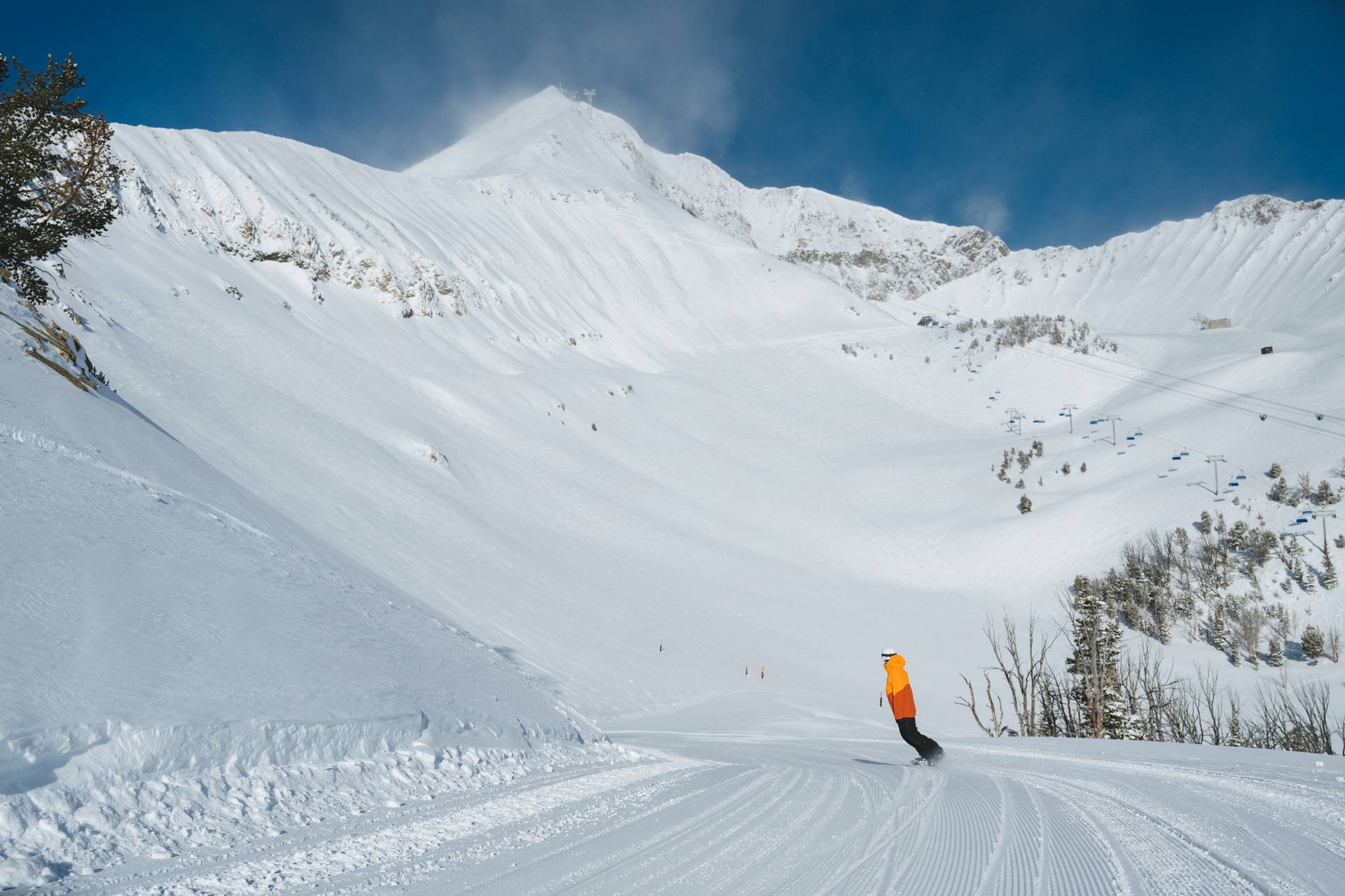 Snowboarder on a groomed run with Lone Peak in the background