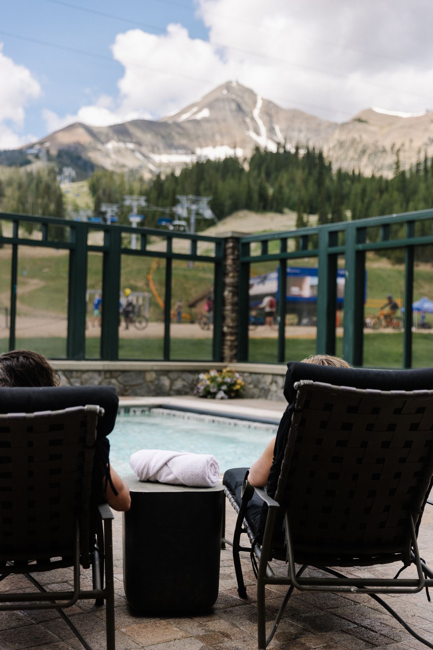 People lounging by a pool with Lone Mountain in the background