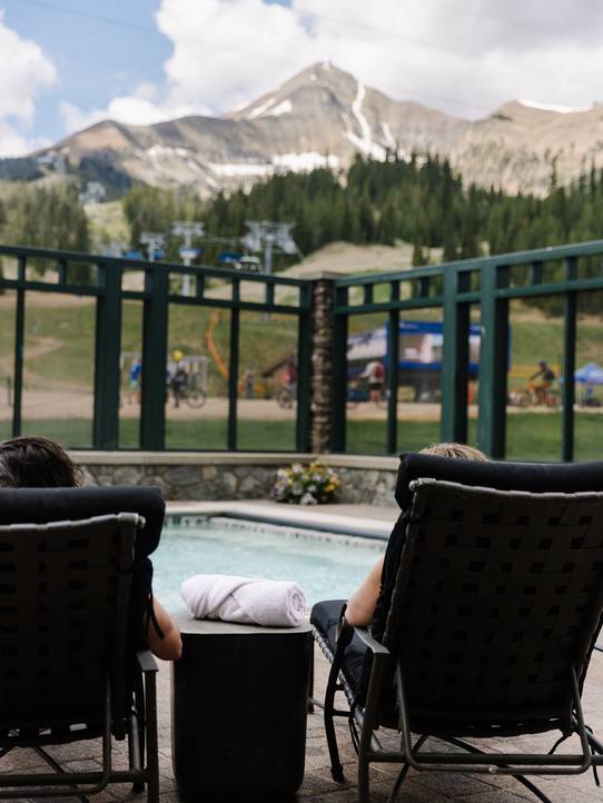 People lounging by a pool with Lone Mountain in the background