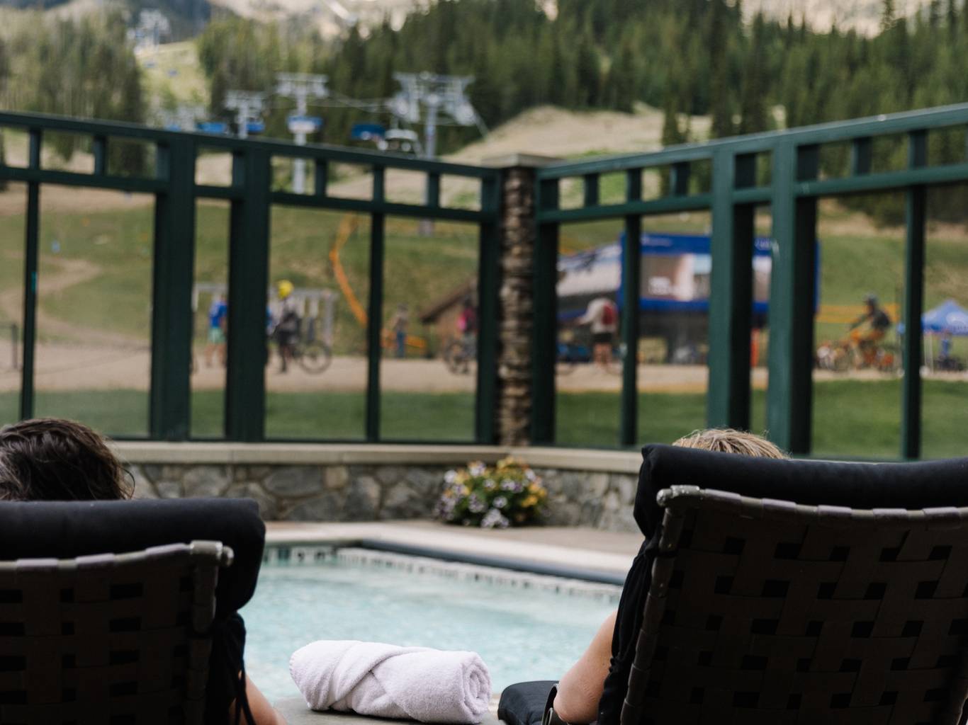 People lounging by a pool with Lone Mountain in the background