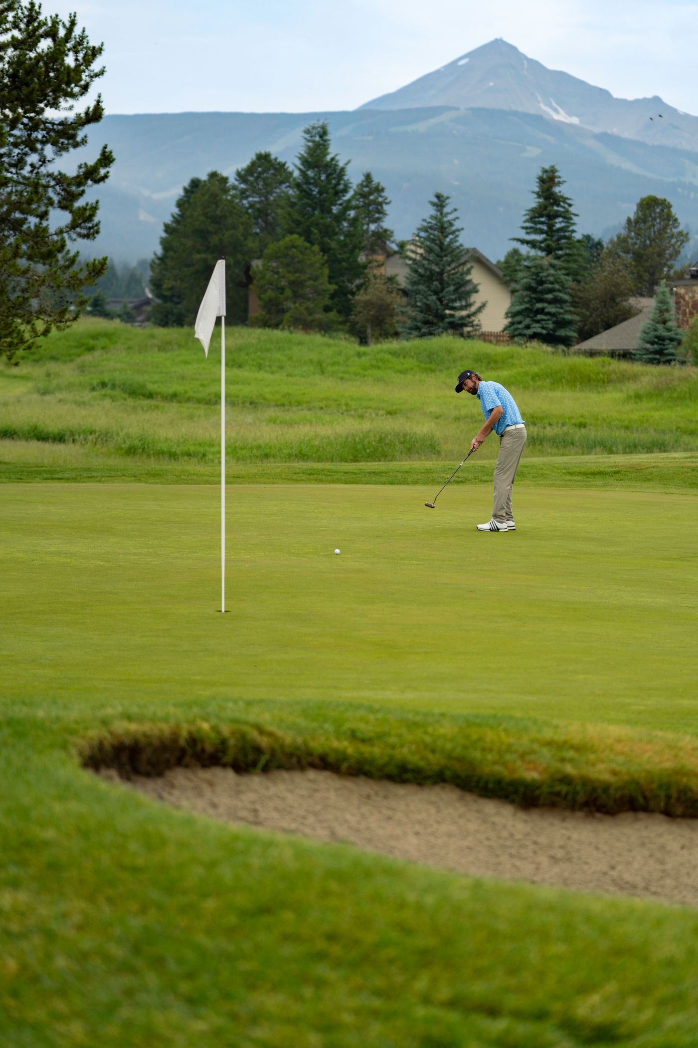 Golfer teeing off with Lone Peak in the background