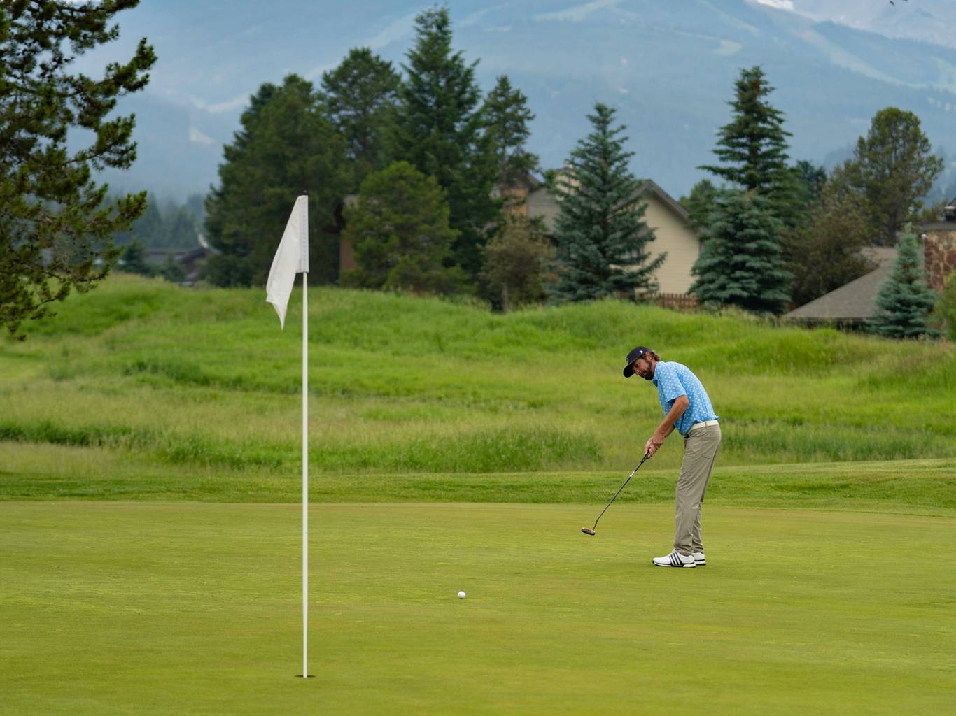 Golfer teeing off with Lone Peak in the background