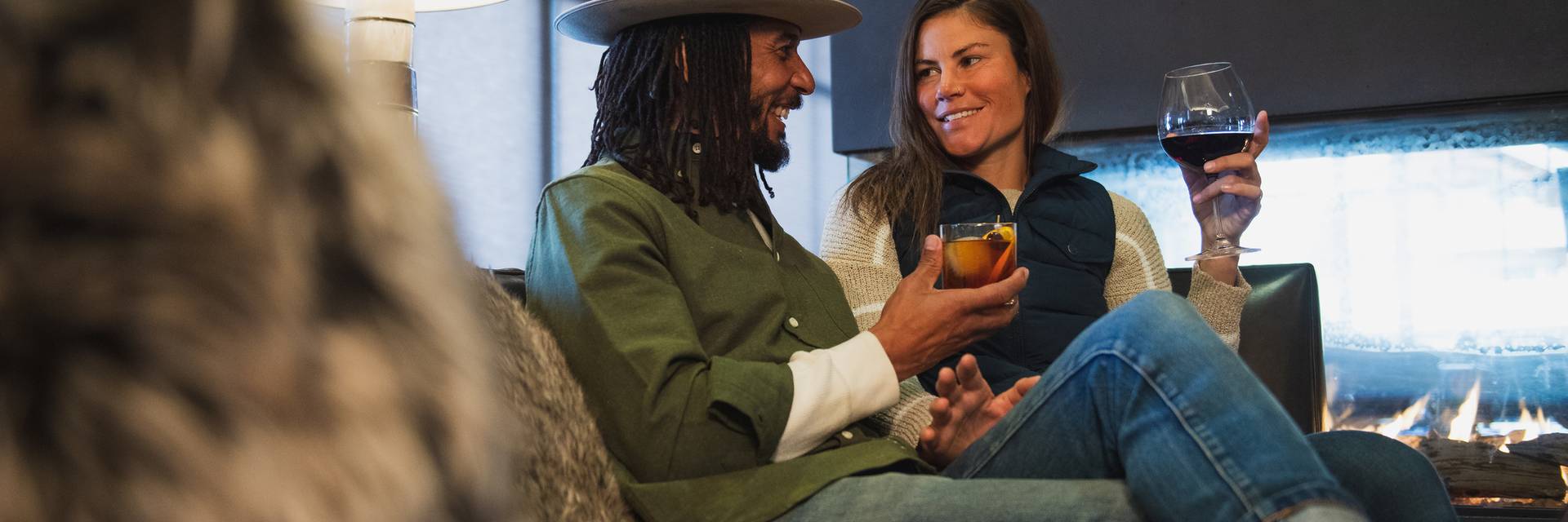 People holding wine glasses in front of a fireplace