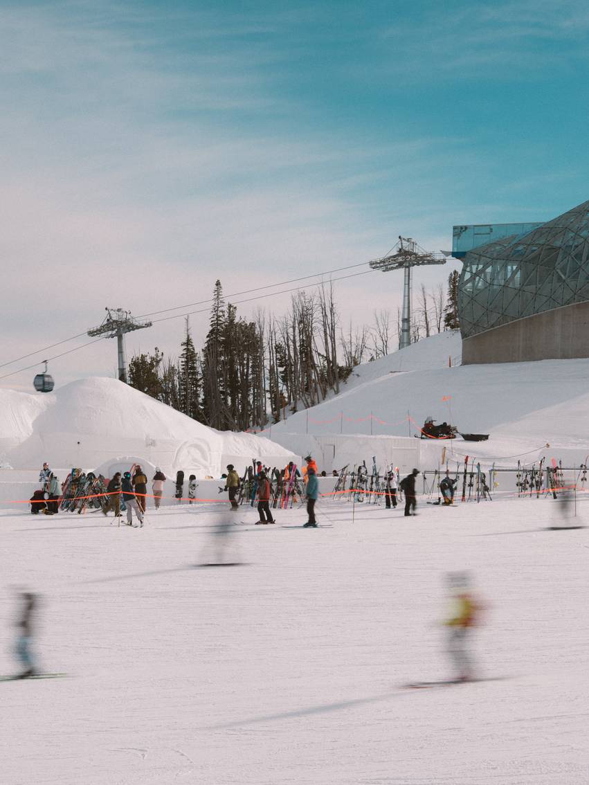 Skiers moving past the Iglu and Lone Peak Tram
