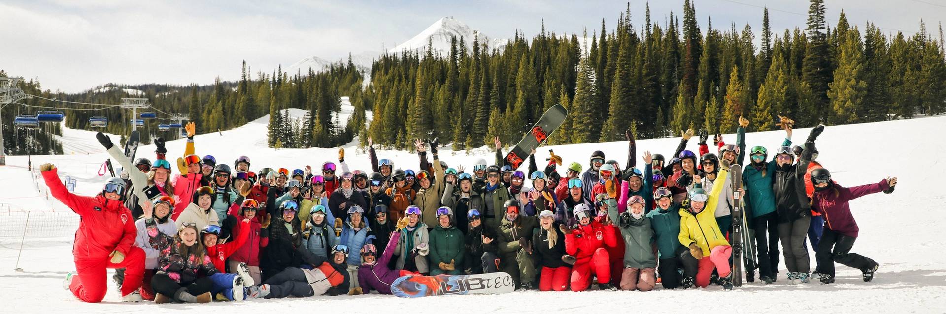 Large group of women in ski and snowboard gear in front of Lone Peak