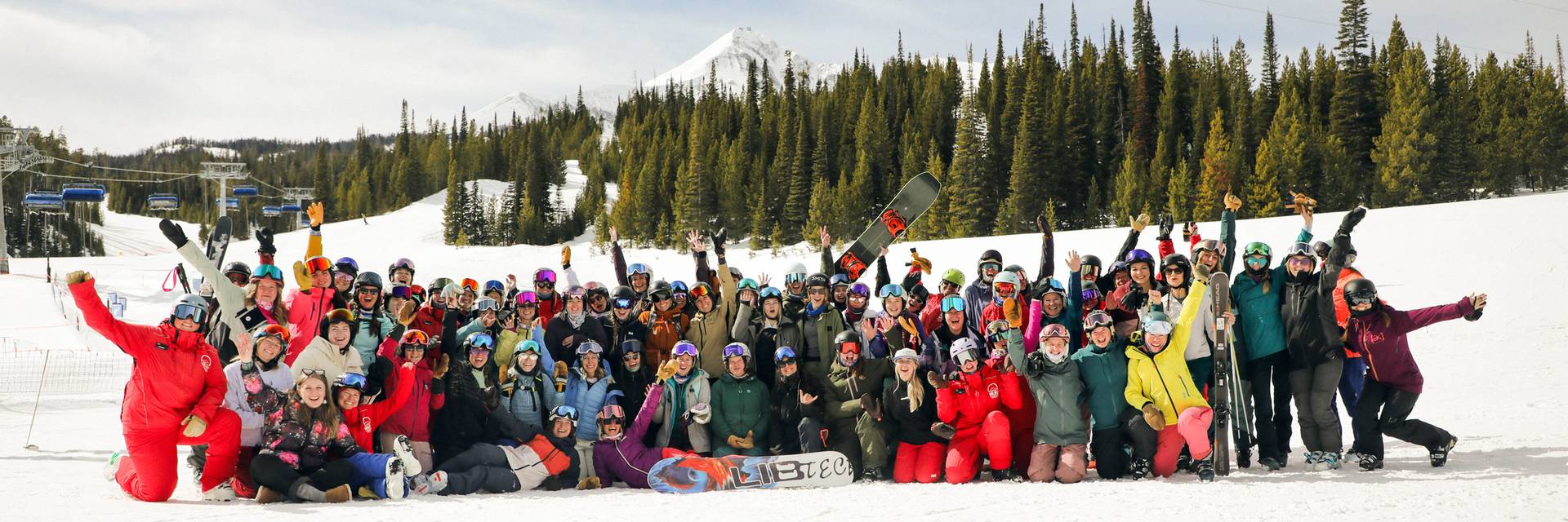 Large group of women in ski and snowboard gear in front of Lone Peak
