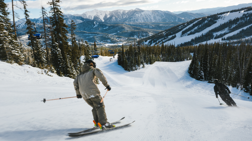Two skiers on a groomed run