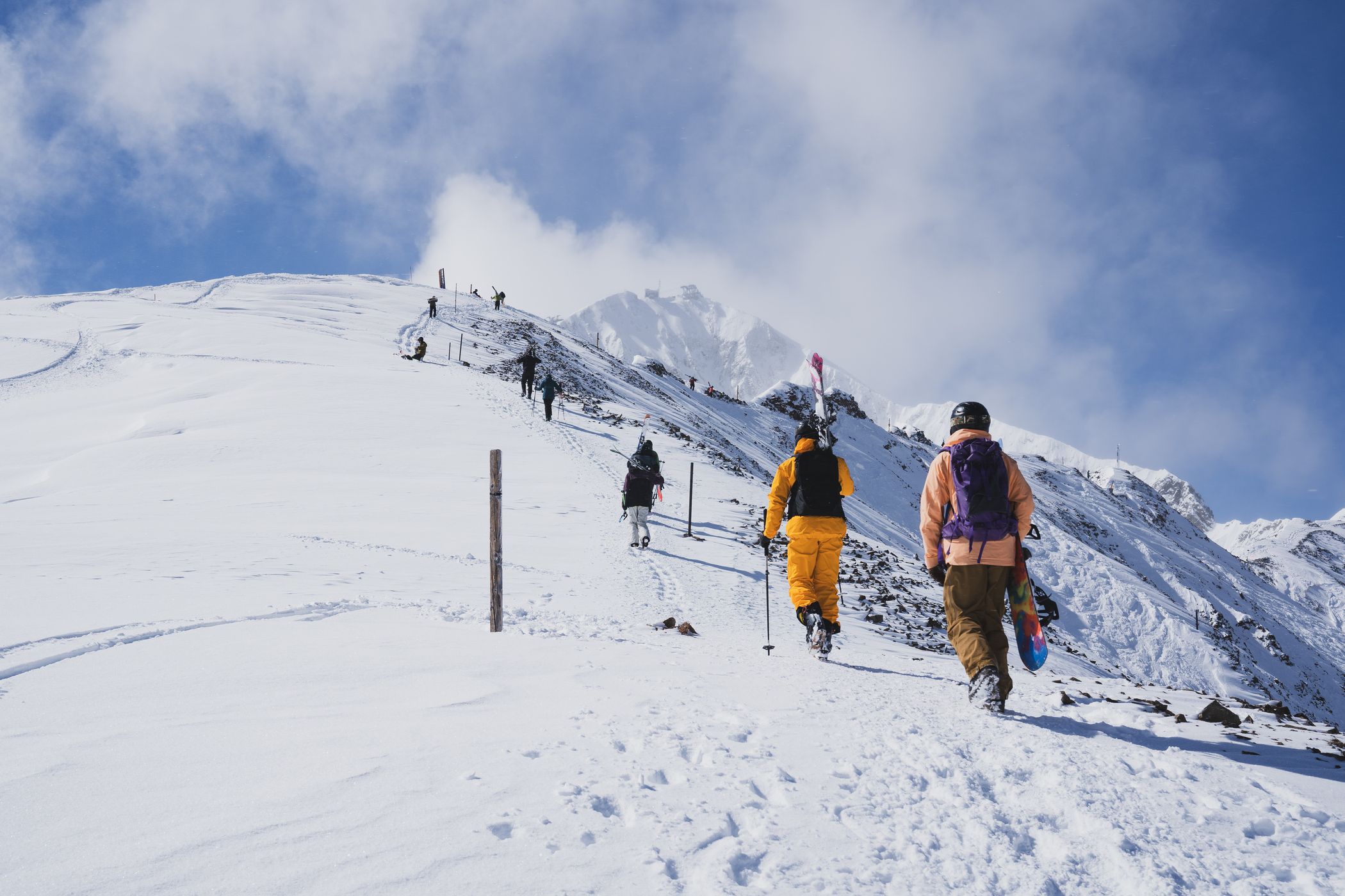 Skiers and snowboarders hiking up a ridge