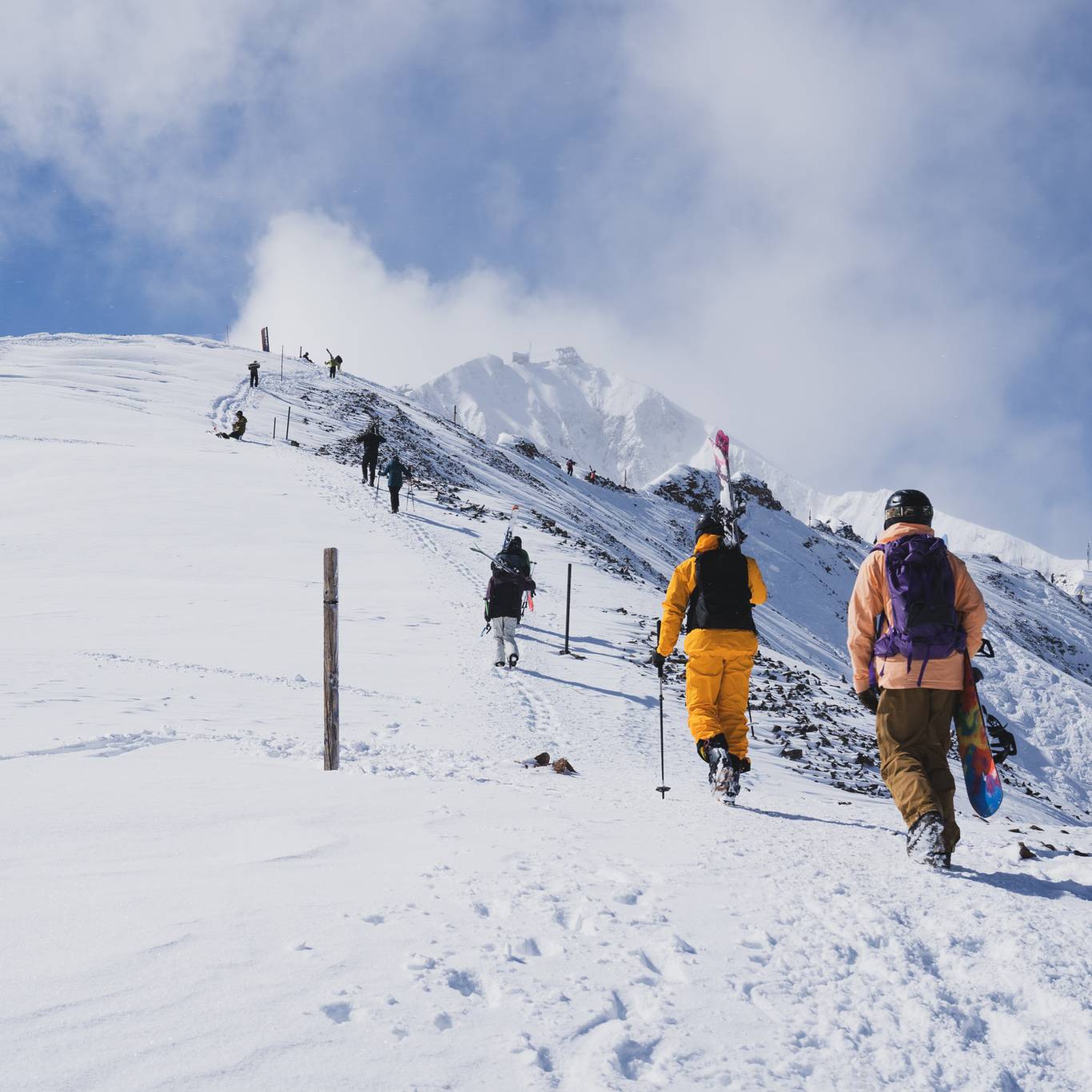 Skiers and snowboarders hiking up a ridge