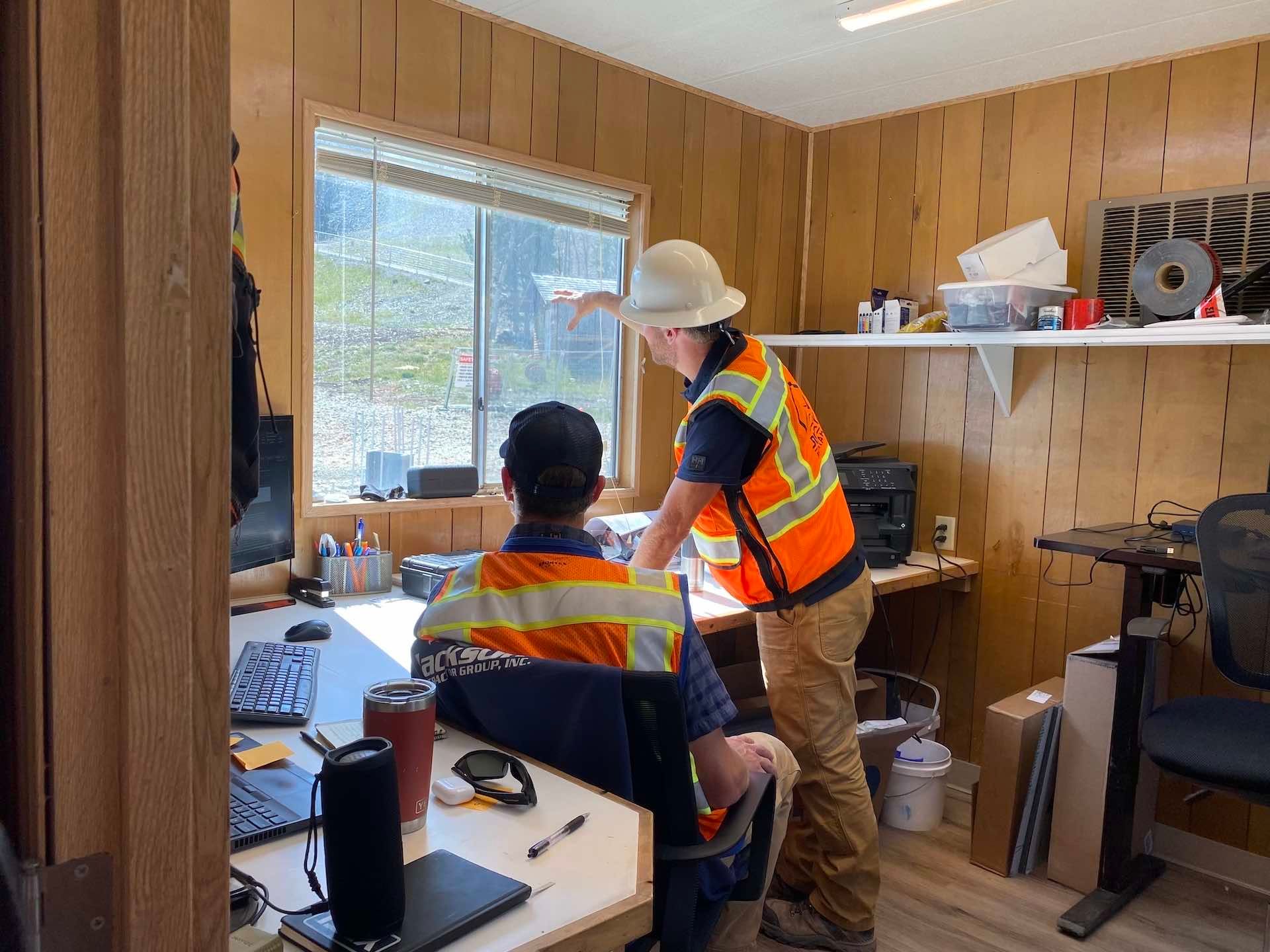 Chad talks with a coworker in a construction trailer