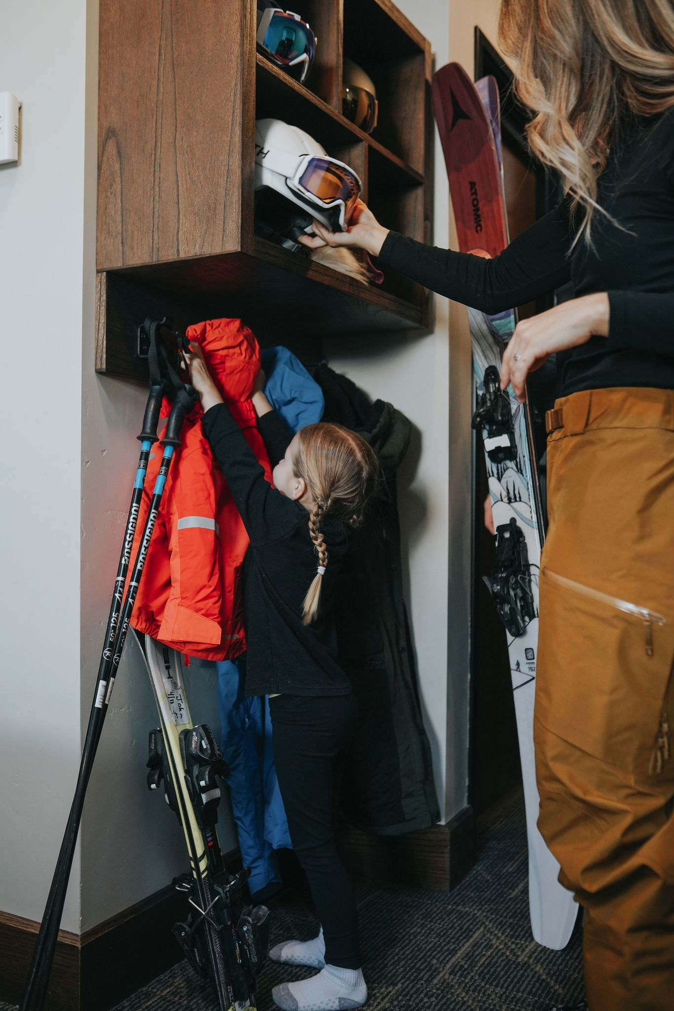 Girl hanging up her ski coat in a hotel room