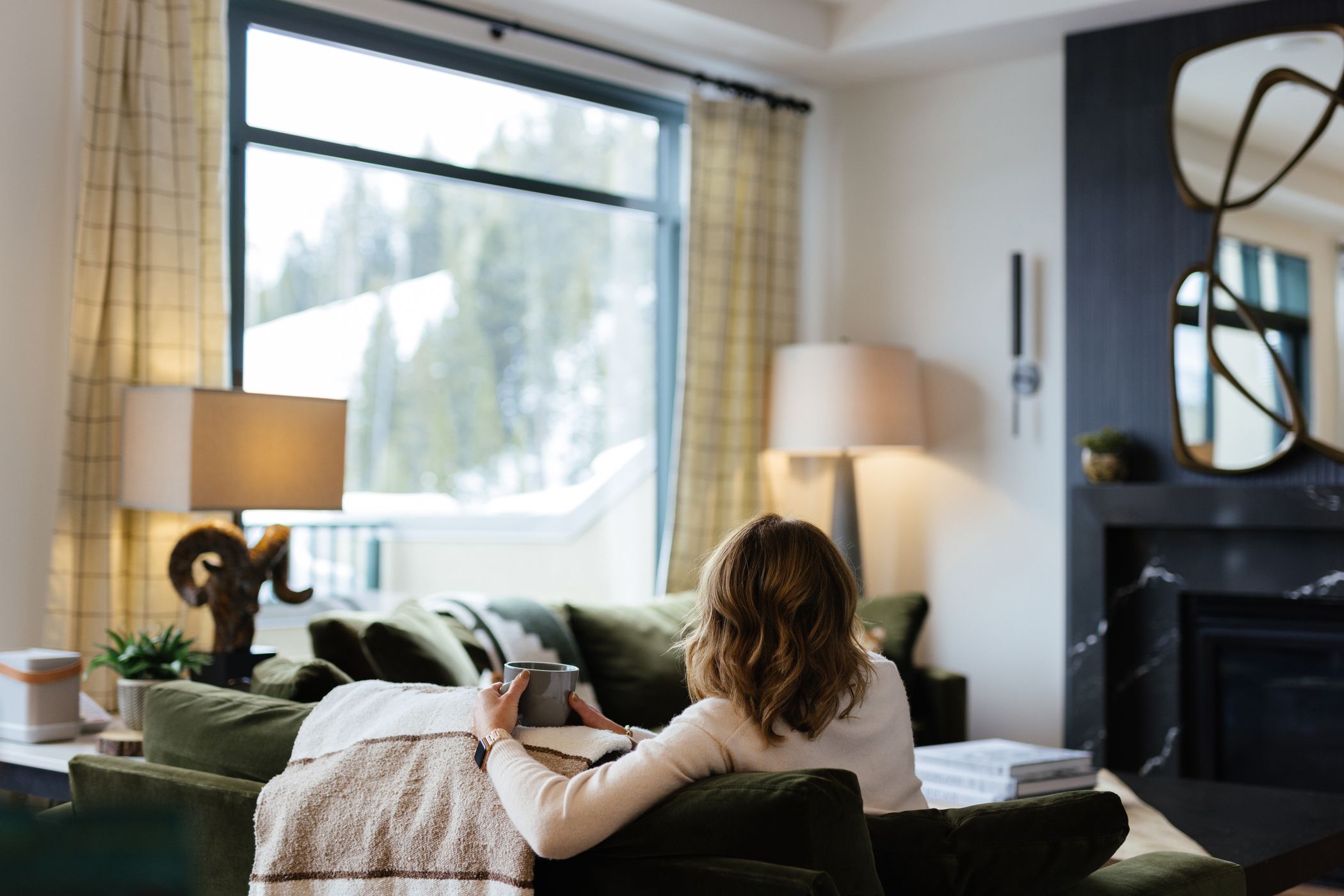 Woman sitting on a couch looking out at a window