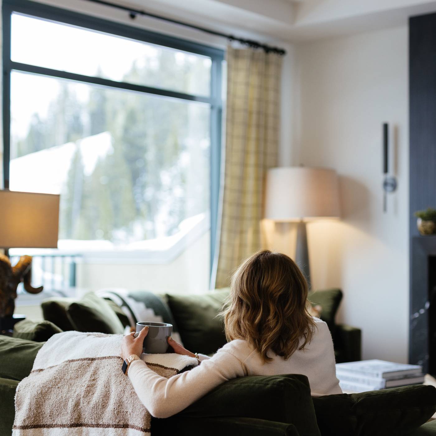 Woman sitting on a couch looking out at a window