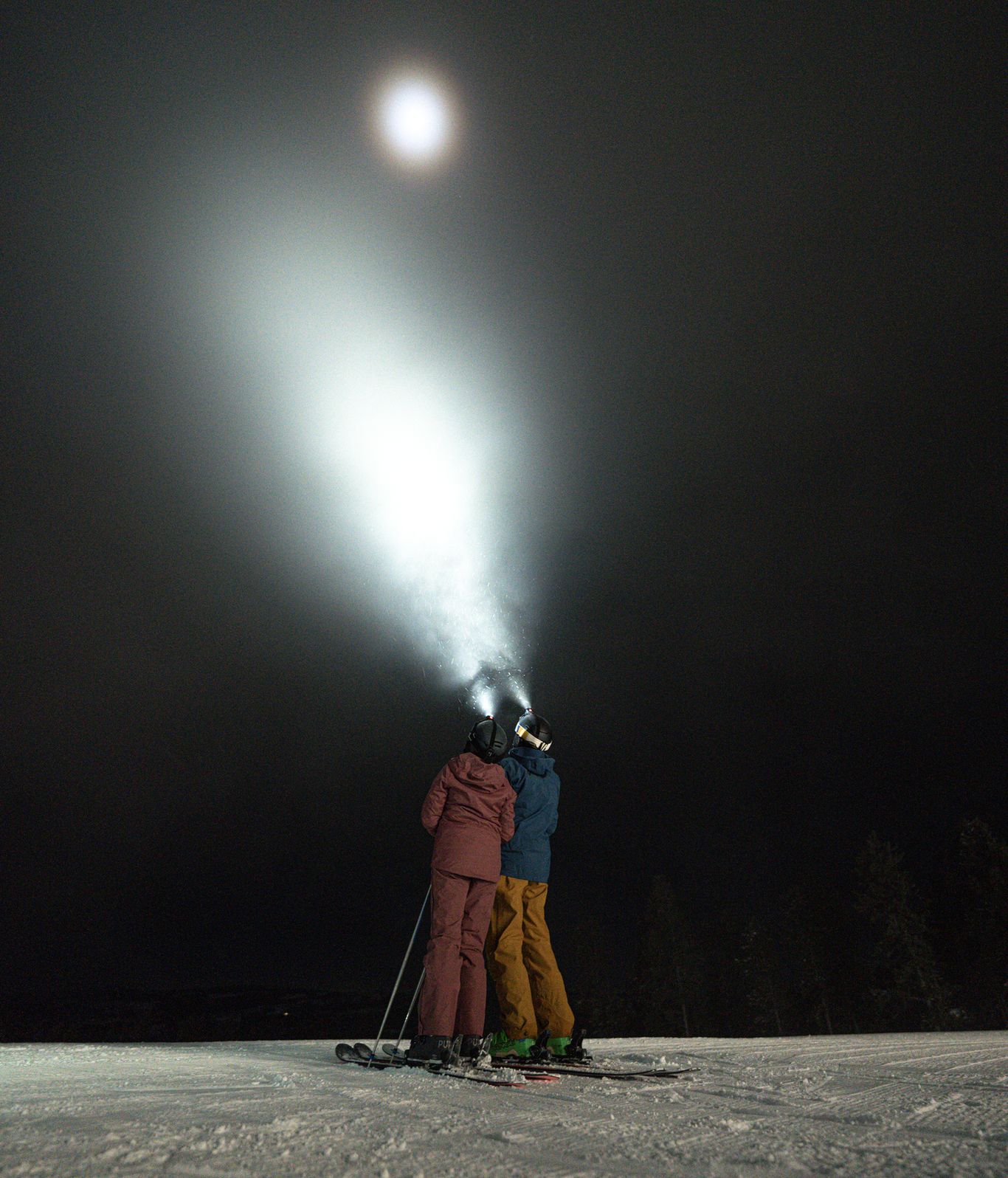 People in ski gear and headlamps looking up at the sky