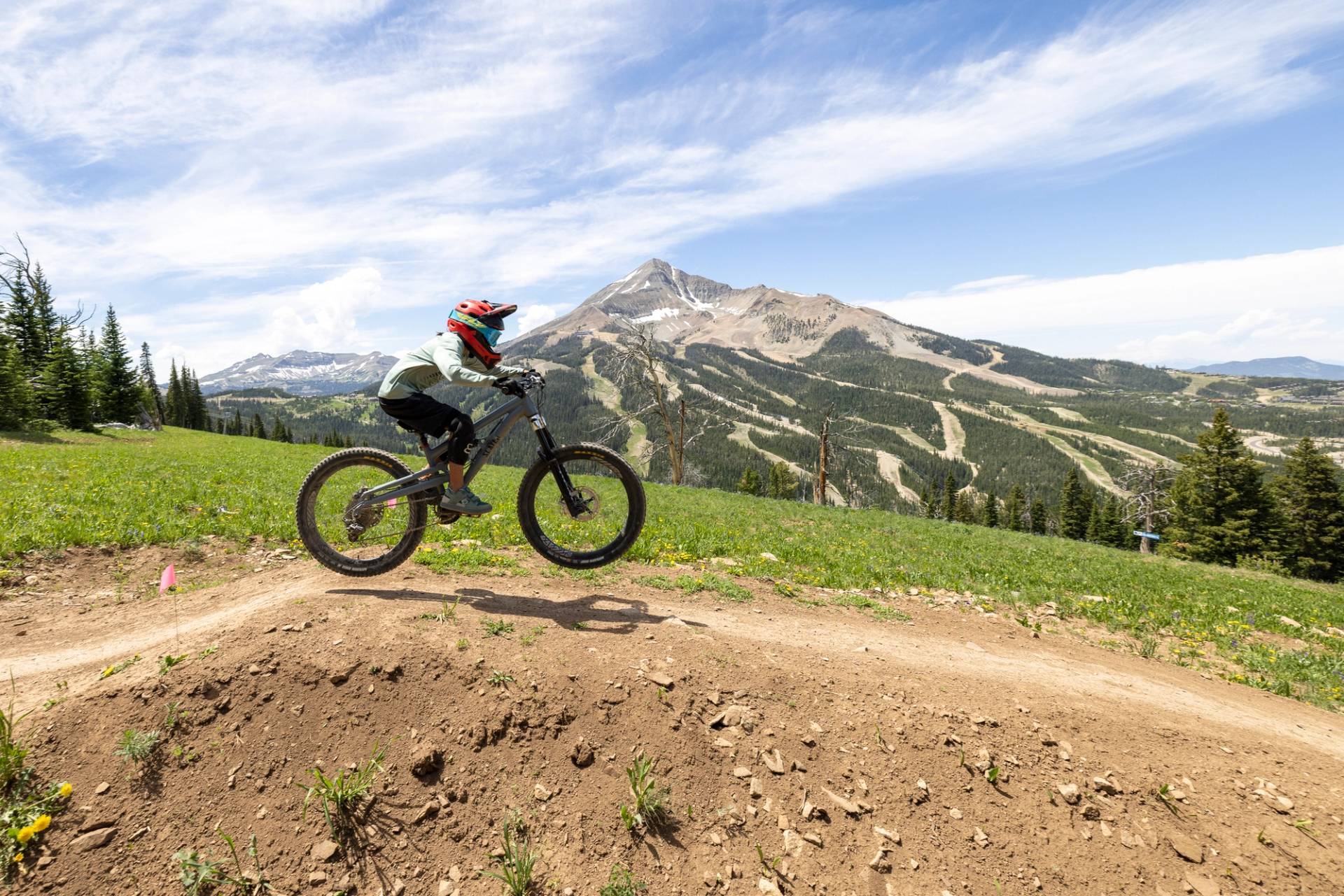 Girl jumping on a mountain bike with Lone Mountain in the background