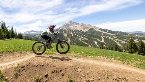 Girl jumping on a mountain bike with Lone Mountain in the background