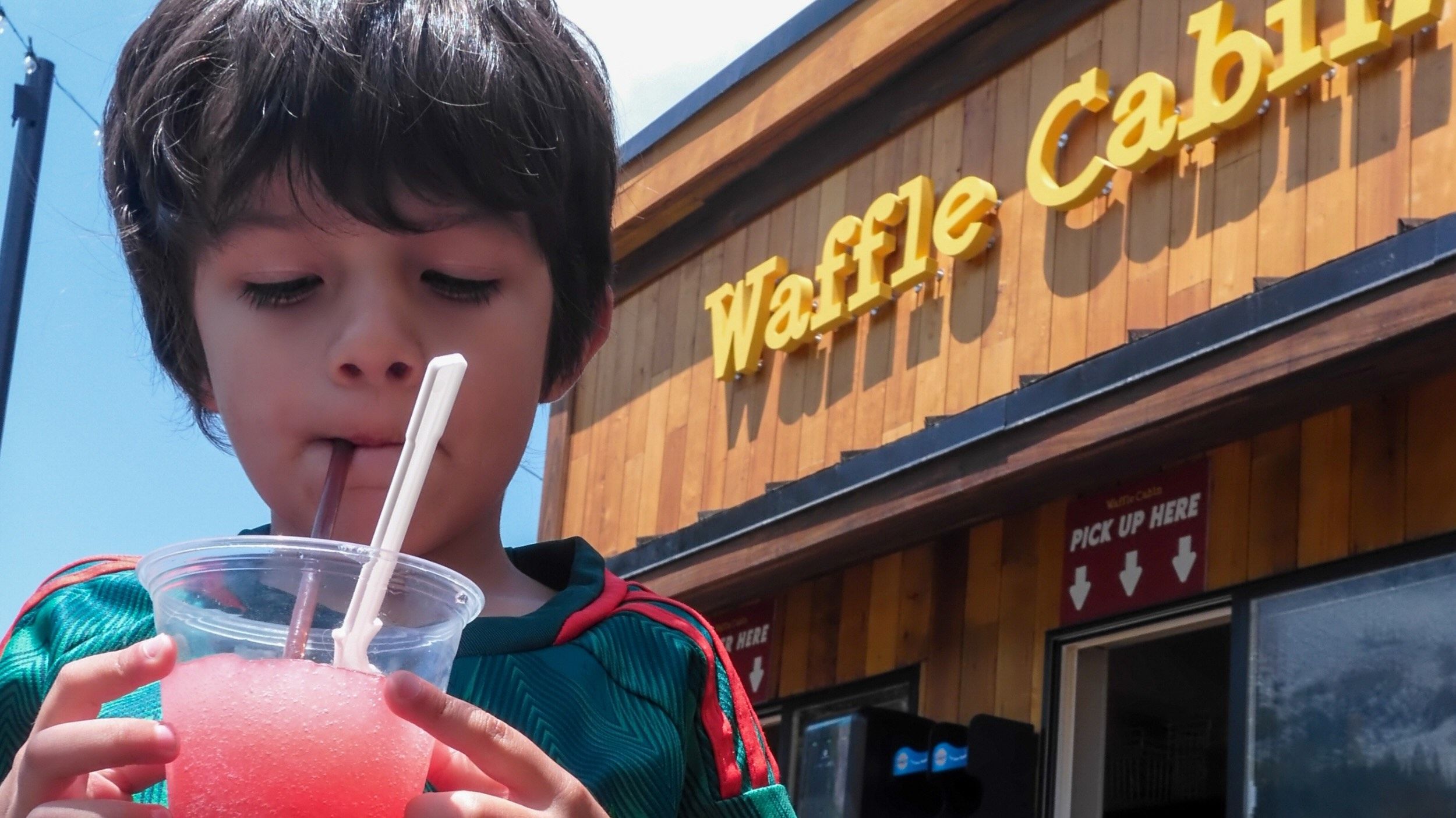 Kid sipping slushy from the Waffle Cabin during the summer